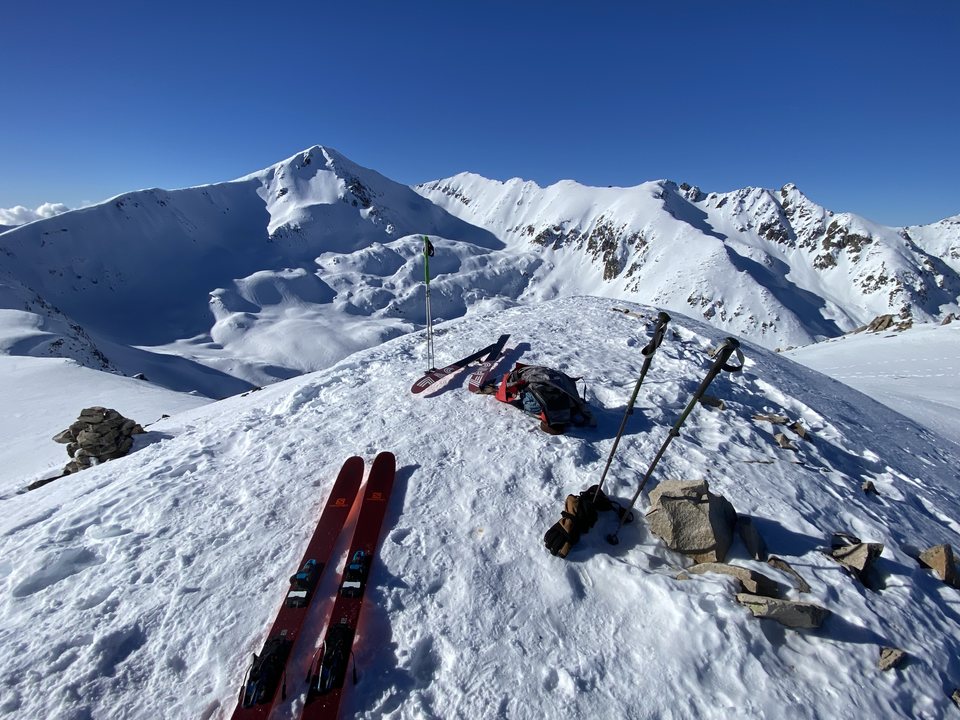 Skis and poles planted on the summit, the ridge ahead