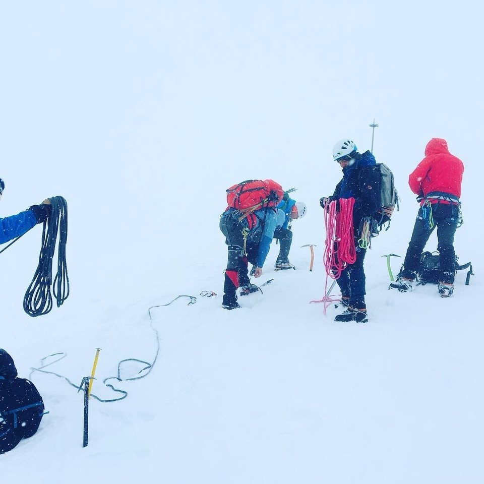 Sorting ropes and ice axes in thick mist and falling snow